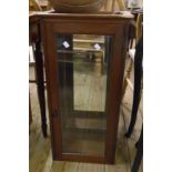 A 14 1/2" stained oak cabinet with mirrored interior enclosed by a glazed panel door