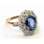 A marked 18ct. yellow metal ring, set with central 3.38ct. pale blue oval sapphire within a