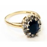 An 18ct. gold ring set with central oval sapphire within a ten stone diamond border