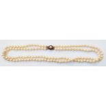 A double string of cultured pearls with marked 9ct. yellow metal ruby and pearl set clasp