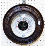 A 10 1/4" diameter early 20th Century carved walnut cased wall barometer with visible aneroid