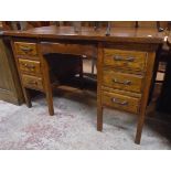 A 4' 1940's stained and polished oak kneehole office desk with central frieze drawer bearing