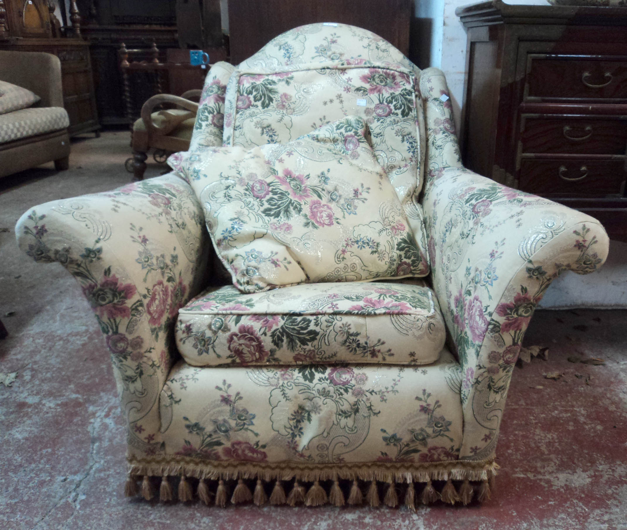 A 20th Century armchair with ornate gilt detailed floral upholstery, swept arms and tassel