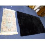 A BLACK RUG, approximate size 242cm x 152cm and a small Chinese pale green ground rug, approximate