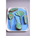 AN ART DECO SILVER AND ENAMELLED FIVE PIECE DRESSING TABLE SET, comprising four brushes and a