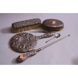 AN EMBOSSED SILVER MOUNTED DRESSING TABLE MIRROR, button hooks and brush (all a/f), together with