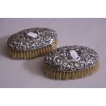A PAIR OF SILVER MOUNTED BRUSHES, having scroll, floral and mask decoration, vacant shields, Chester