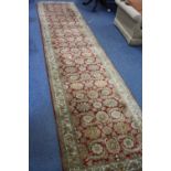 AN OLIVE GREEN AND RED GROUND CARPET RUNNER, 100% wool pile, hand knotted in India, approximate size
