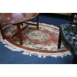 A CHINESE RED GROUND OVAL RUG, approximate size 178cm x 114cm