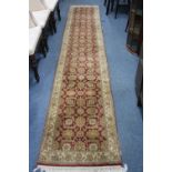 AN OLIVE GREEN AND RED GROUND CARPET RUNNER, 100% wool pile, hand knotted in India, approximate size