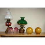 TWO OIL LAMPS, with four various glass shades