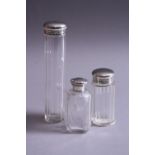 TWO GEORGE V SILVER TOPPED GLASS TOILET JARS, London 1917, together with another toilet jar with a