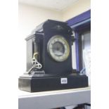 A BLACK SLATE MANTEL CLOCK, having architectural top with mask pediment over Arabic numerals chapter