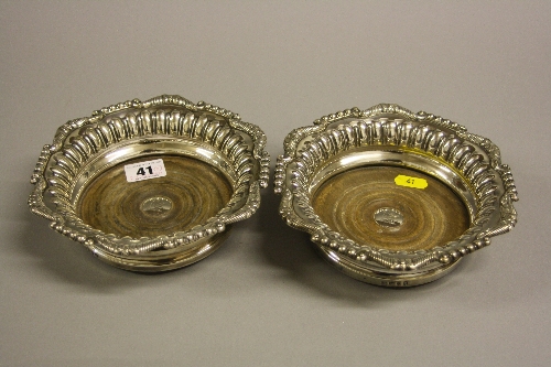 A PAIR OF SILVER BOTTLE COASTERS, having fluted interior border to shaped beaded and scrolled