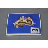 A RECTANGULAR CERAMIC PLAQUE, having hand painted relief decoration depicting cherubs with grapes on