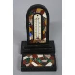 AN ASHFORD MARBLE DESK THERMOMETER, the thermometer supported on dome topped specimen inlaid arch on