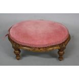 A VICTORIAN CARVED WALNUT FRAMED OVAL FOOTSTOOL, with pink upholstery, approximately 36cm x 28cm x