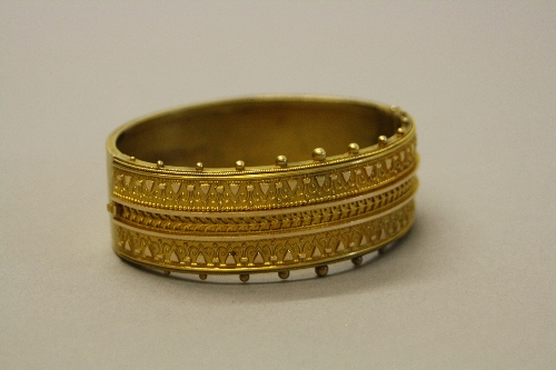 A LATE VICTORIAN GOLD CUFF BANGLE, circa 1880, the hinged top with Etruscan style wirework and