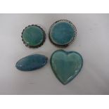 TURQUOISE GLAZED RUSKIN POTTERY, comprising three cabochon set white metal brooches, all marked