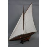 A PAIR OF WOODEN MODEL YACHTS ON STANDS, both with sails at full mast, approximate height 106cm x