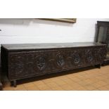 A LARGE 18TH CENTURY OAK SWORD CHEST, having carved front panel with four roundels depicting mask