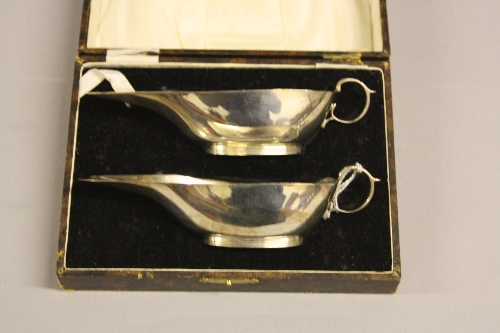 TWO CASED SILVER SAUCE BOATS, having elongated flat top, ribbed circular foot, high loop handle,