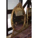 A MID 19TH CENTURY GILT FRAMED OVAL OVERMANTEL MIRROR, the cresting of merchildren flanking a