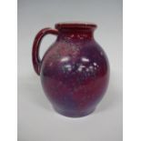 A RUSKIN POTTERY HIGH FIRED EWER OR HANDLED VASE, having green spotting to red and purple sang de