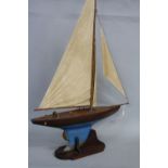 AN EARLY 20TH CENTURY MODEL YACHT, wooden with painted finish and metal keel, on a mahogany stand,