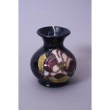 A SMALL MOORCROFT POTTERY VASE, purple Magnolia pattern on dark blue ground, impressed and painted