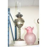 A LATE VICTORIAN BRASS BASED OIL LAMP, cranberry glass shade, white glazed circular ceramic base,