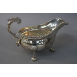 AN EDWARDIAN GOLDSMITHS & SILVERSMITHS CO LTD SILVER SAUCEBOAT, gadrooned rim, cast scrolled handle,