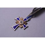 A GERMAN WWII 3RD REICH MOTHERS CROSS, complete with ribbon, all the blue and white enamel is intact