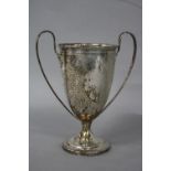 AN EDWARDIAN SILVER TWIN HANDLED TROPHY CUP, elongated plain handles, the cup with scrolled border