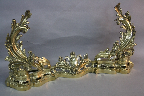 A LATE VICTORIAN/EDWARDIAN BRASS FENDER, of Rococo style, comprising of three sections which slide