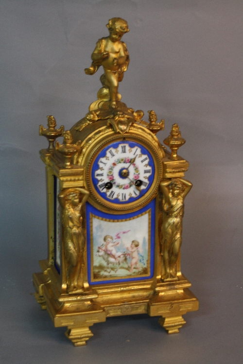 A MID 19TH CENTURY STYLE GILT METAL MANTEL CLOCK, putti surmounting an arched top with circular