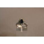 A MODERN PLATINUM SAPPHIRE AND DIAMOND OVAL CLUSTER RING, one oval mixed cut blue sapphire measuring