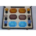 A CASED SET OF ART DECO COLOURED INTAGLIO GLASS, comprising six pin dishes and six stoppers, each