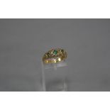AN EARLY 20TH CENTURY 18CT GOLD EMERALD AND DIAMOND HALF HOOP RING, open pierced work design sides