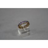 A MODERN YELLOW METAL TANZANITE FULL ETERNITY RING, round mixed cut Tanzanites claw set, ring