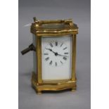 A 20TH CENTURY BRASS CASED CARRIAGE CLOCK OF SERPENTINE OUTLINE, enamel dial, Roman numerals, height