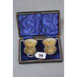 A CASED PAIR OF EDWARDIAN SILVER SALTS, of thistle form, embossed decoration, gilt interiors,