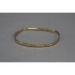 A LATE 20TH CENTURY 9CT GOLD BANGLE, 'TV' shape, half engraved in diamond cut border, measuring