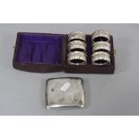 A CASED SET OF SIX EDWARDIAN SILVER NAPKIN RINGS, of circular form with crimped edges and embossed