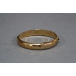 A LATE 20TH CENTURY OVAL HINGED BANGLE, diamond cut design, measuring approximately 68mm x 60mm by a