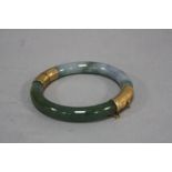 A MODERN JADE BANGLE, round in shape, hinged, measuring approximately 75mm in diameter, jade