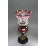 AN OIL LAMP, with cranberry glass reservoir and glass shade