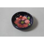 A SMALL MOORCROFT POTTERY FOOTED BOWL, 'Clematis' pattern on blue ground, impressed marks to base,