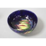 A MOORCROFT POTTERY FOOTED BOWL, leaf and berry pattern on a blue ground, impressed and painted