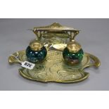 AN ART NOUVEAU STYLE BRASS INKSTAND, stamped 'Geschutz', fitted with two iridescent green glass